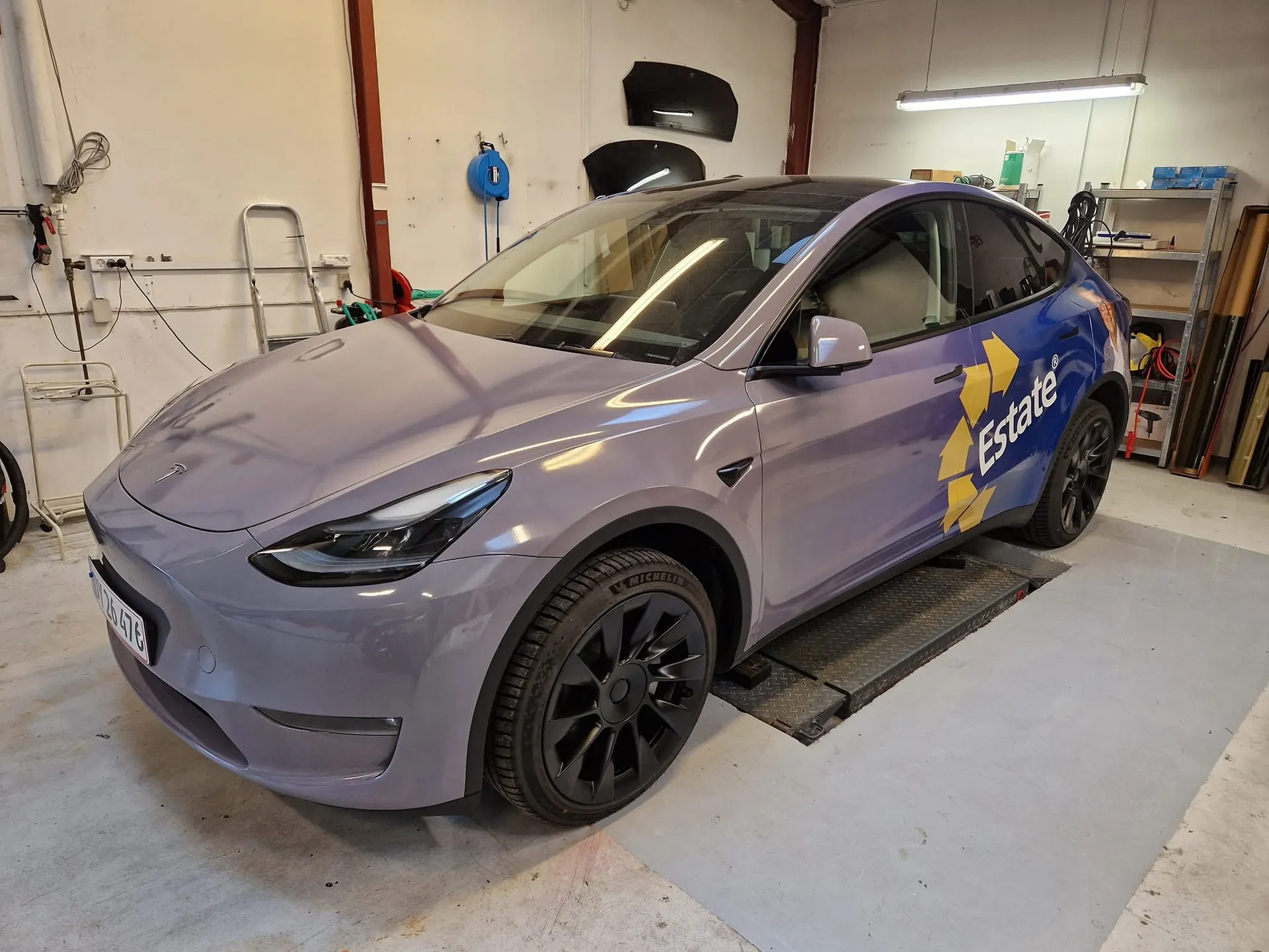Tesla folieret med Estate-bilreklame i blåt og gult