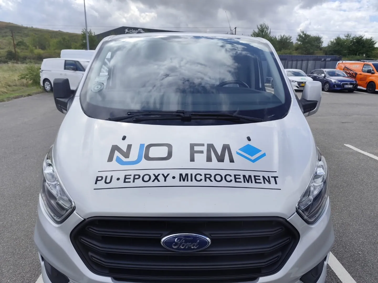 Hvid Ford Transit med NJO FM-reklame på fronten