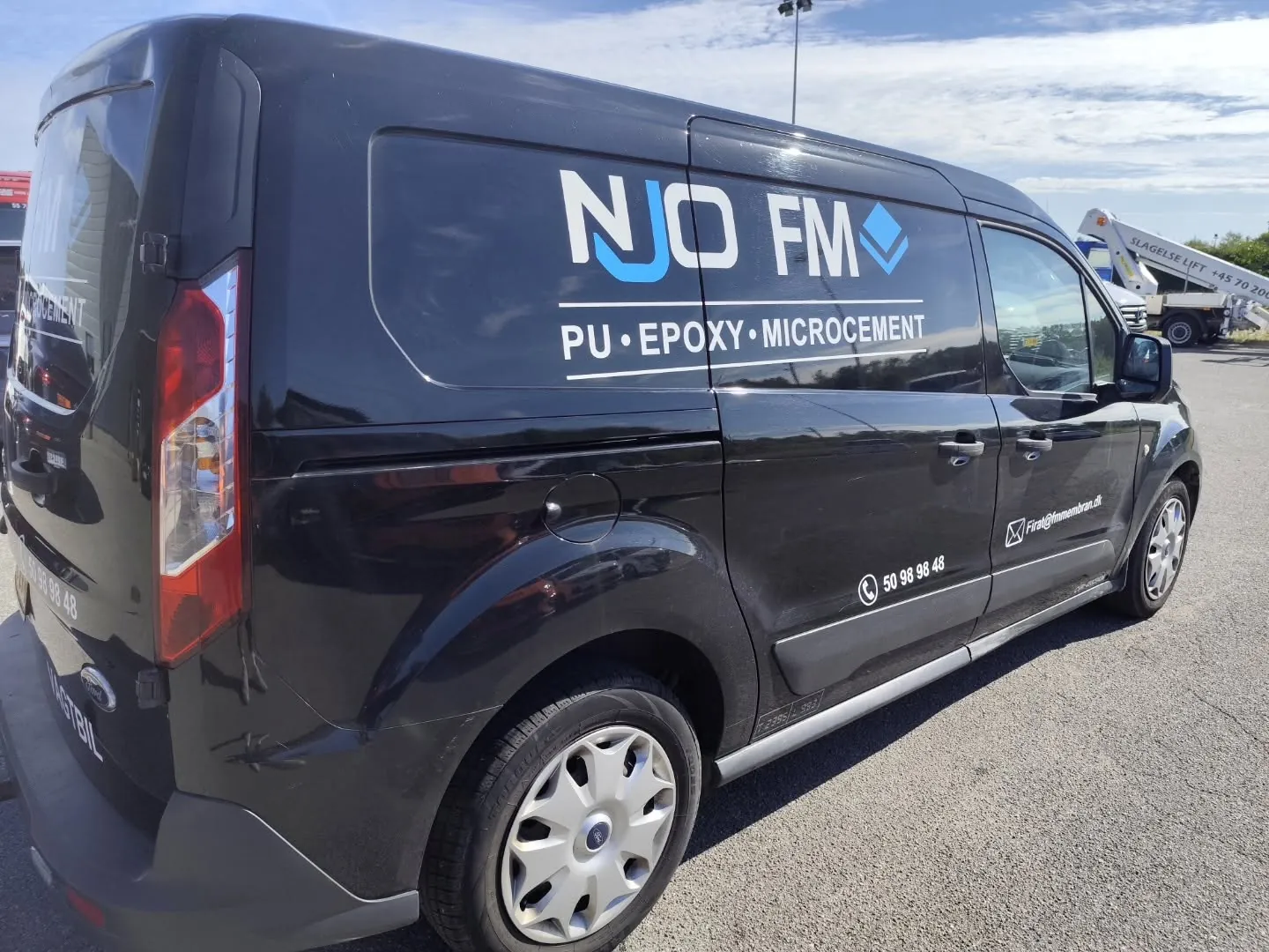 Mørk Ford Transit med NJO FM-reklame på siden